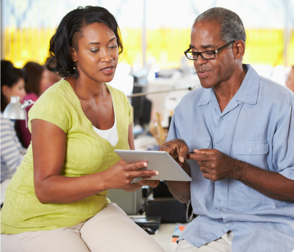 A woman and an older man looking at a tablet together