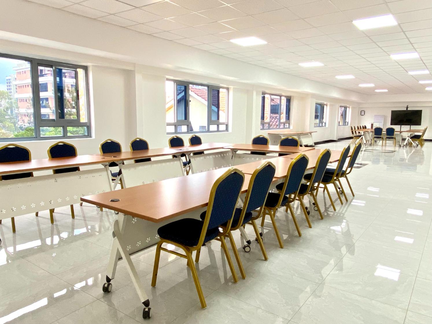 An Enwealth conference room set with long tables and chairs by the windows