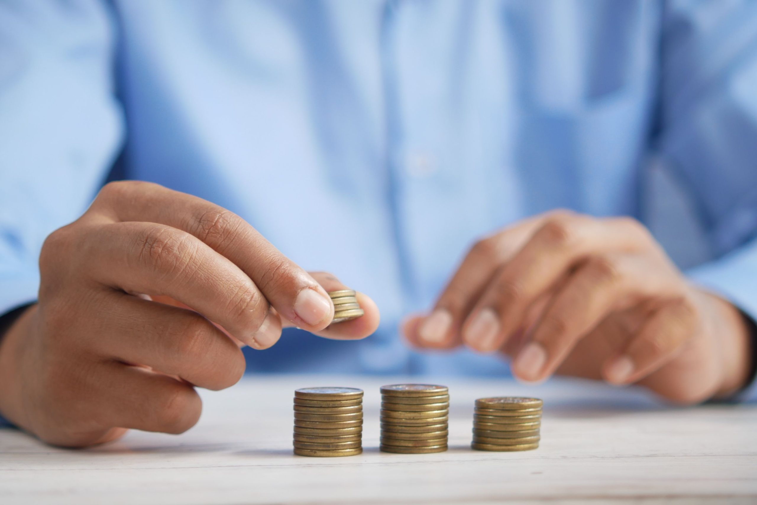 A man placing a coin on one of three coin stacks