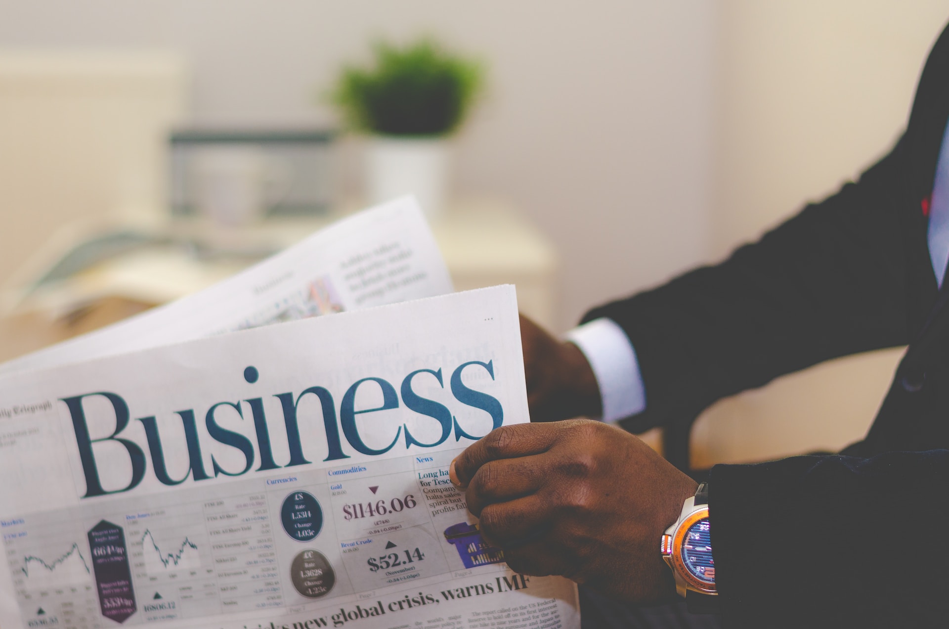 A man in a suit reading a Business newspaper