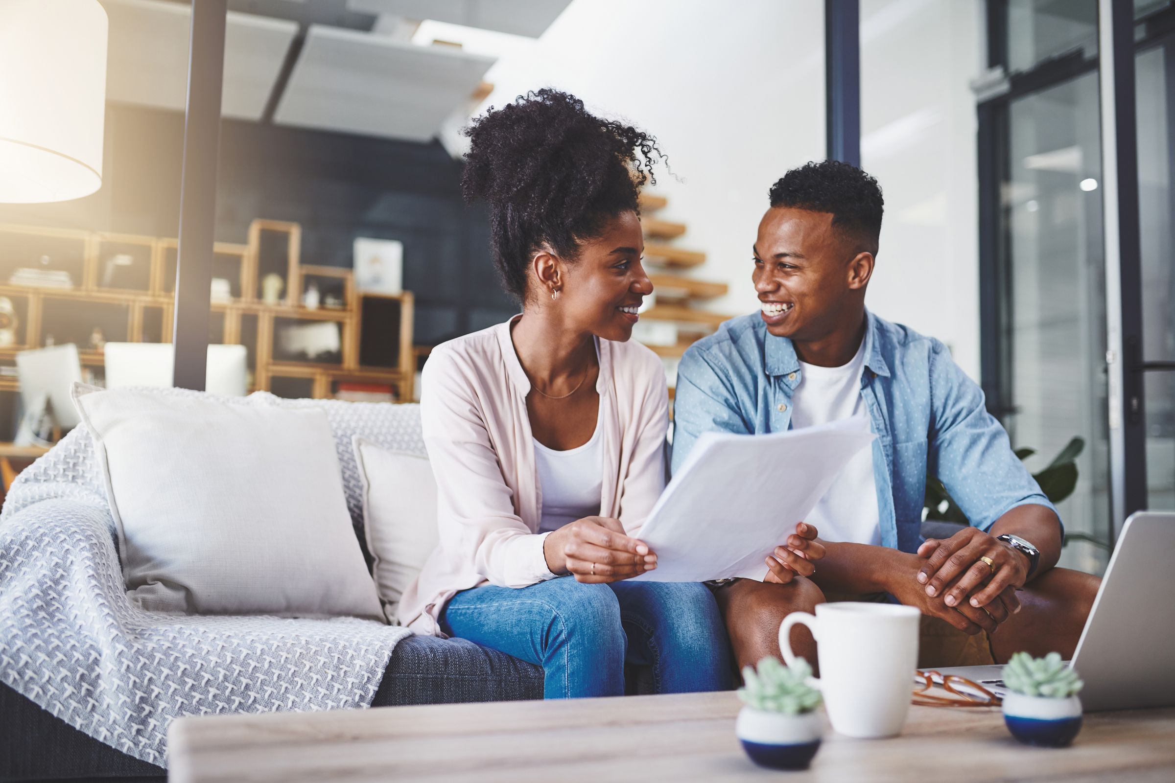 A young couple on a sofa going over their papers together, smiling