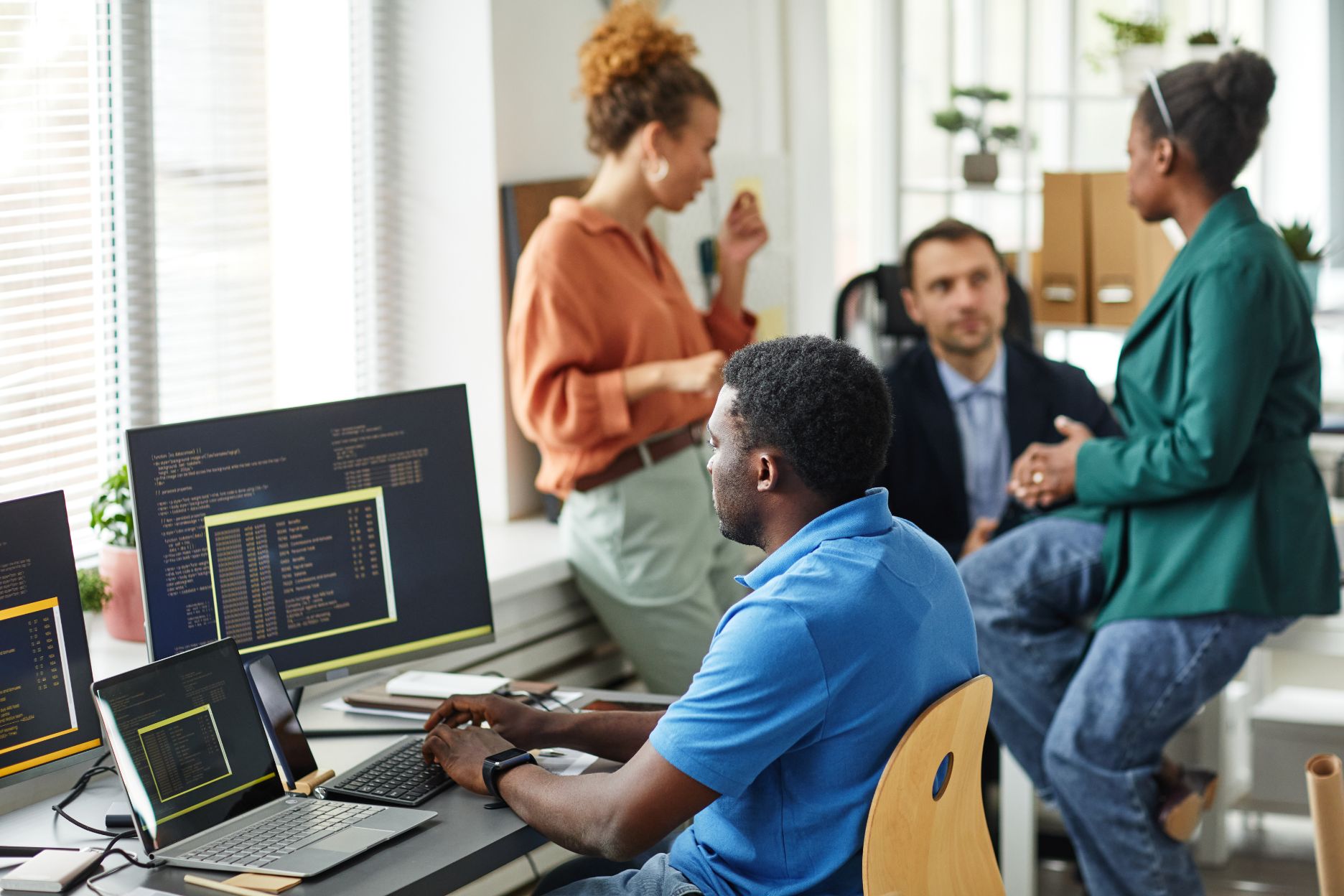 Colleagues working at computers and talking in a modern office
