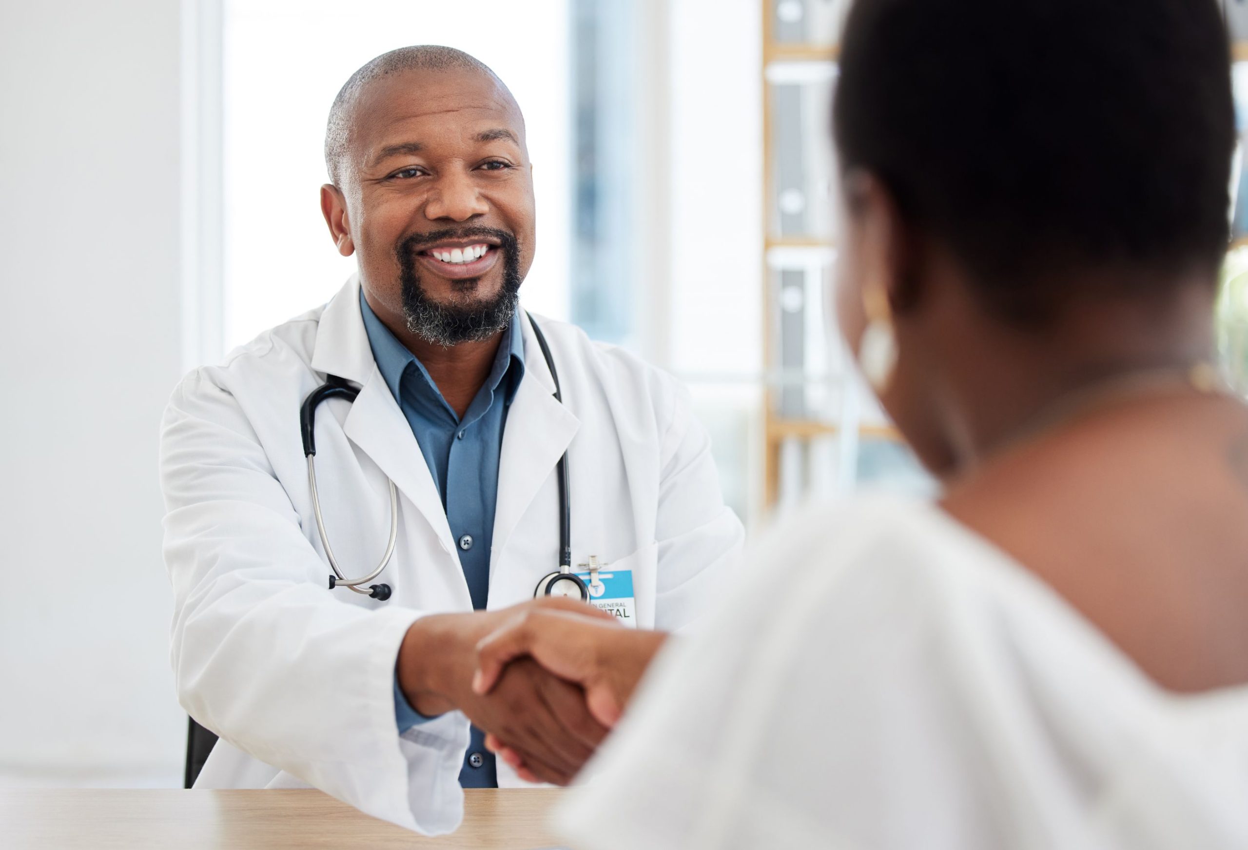 A doctor in a white coat shaking hands with a patient