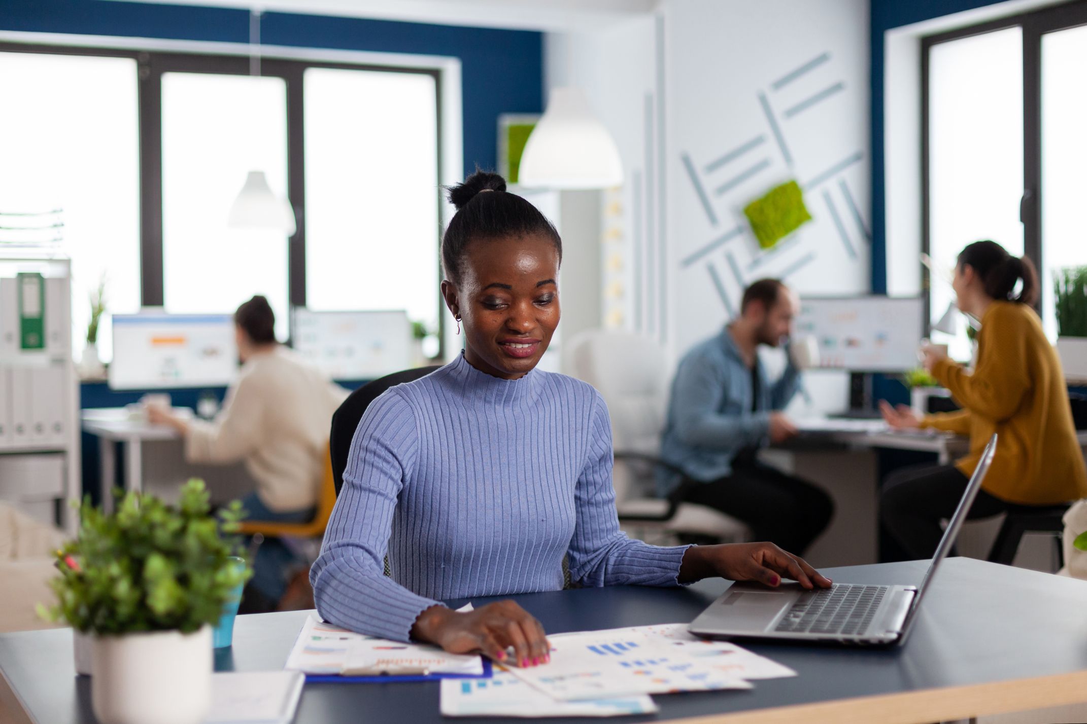 A woman working at a laptop in an open-plan office