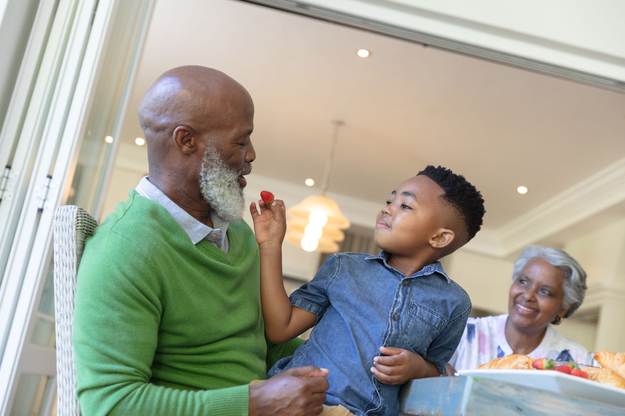 A grandfather and grandmother sharing a snack with their grandson
