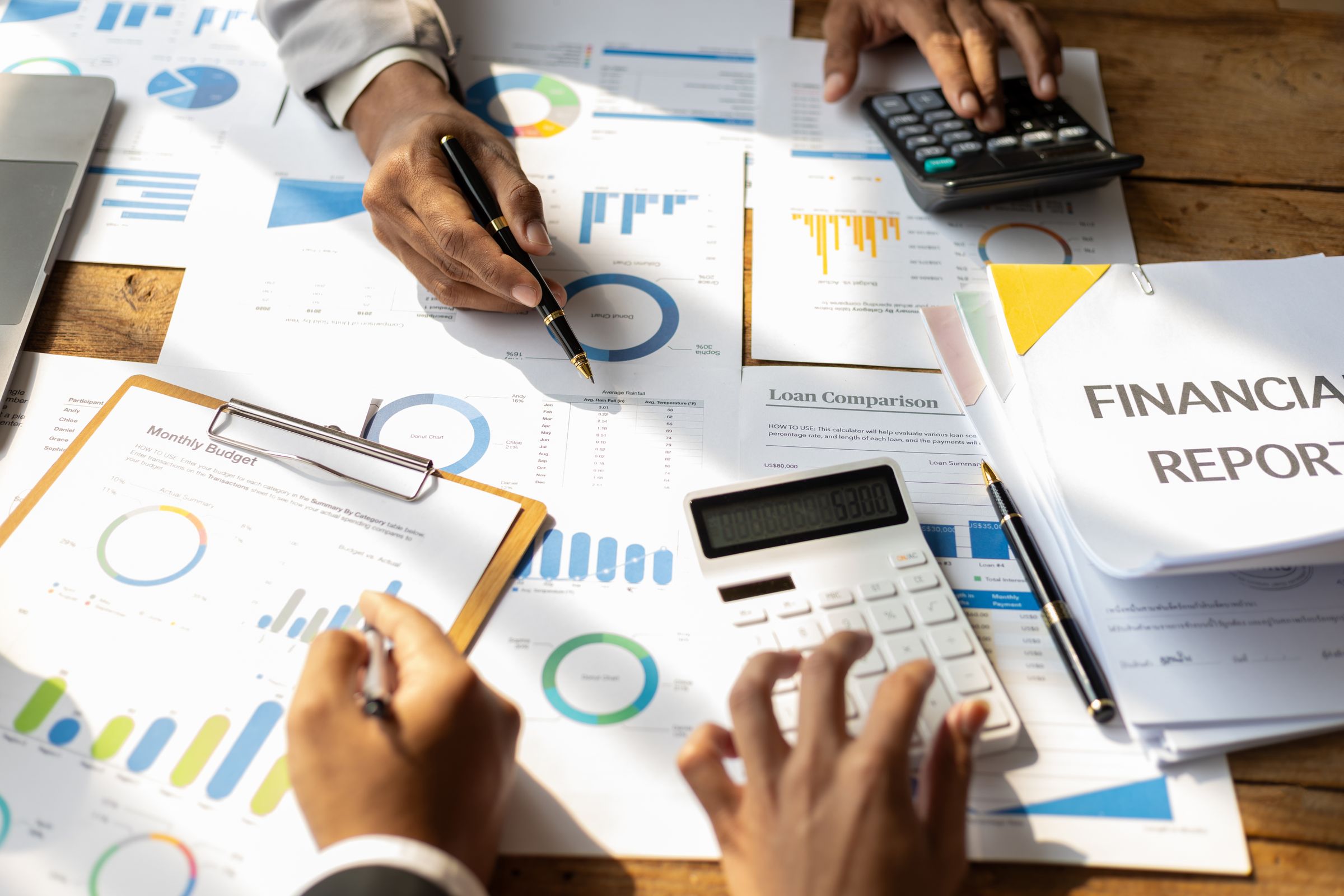 Hands going over printed financial reports with a calculator