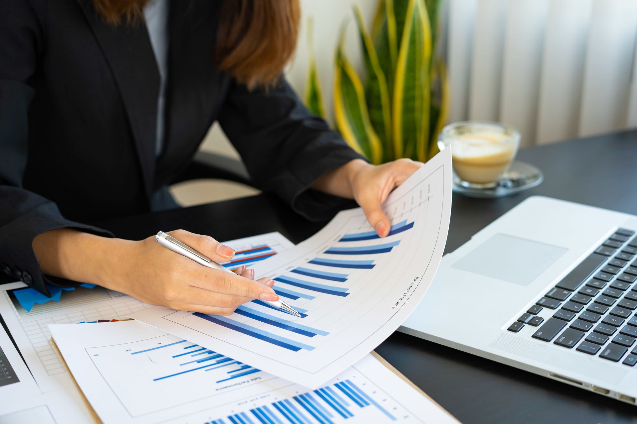 A woman reviewing printed bar charts beside a laptop