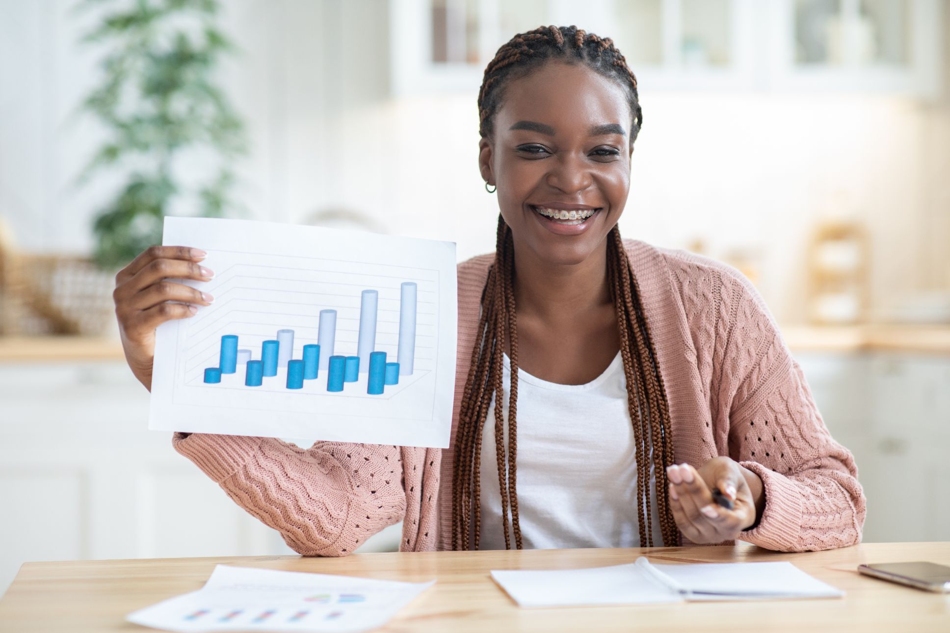 A smiling woman at a desk holding up a bar chart