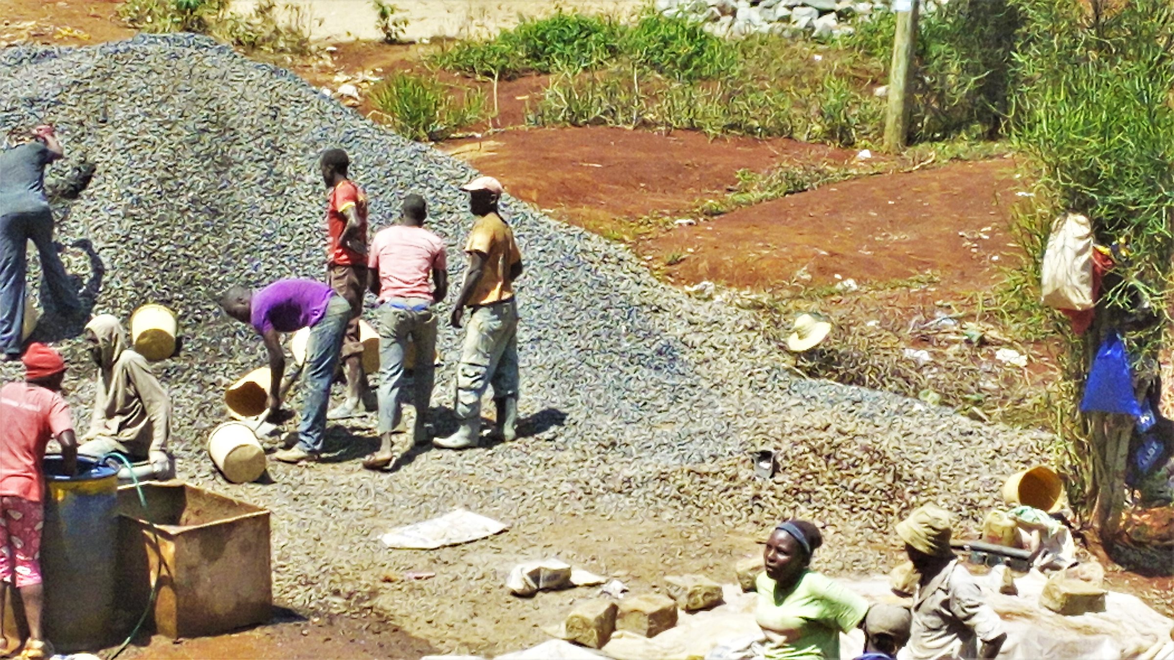 Building workers loading ballast and water into a concrete mixer in Embu, Kenya