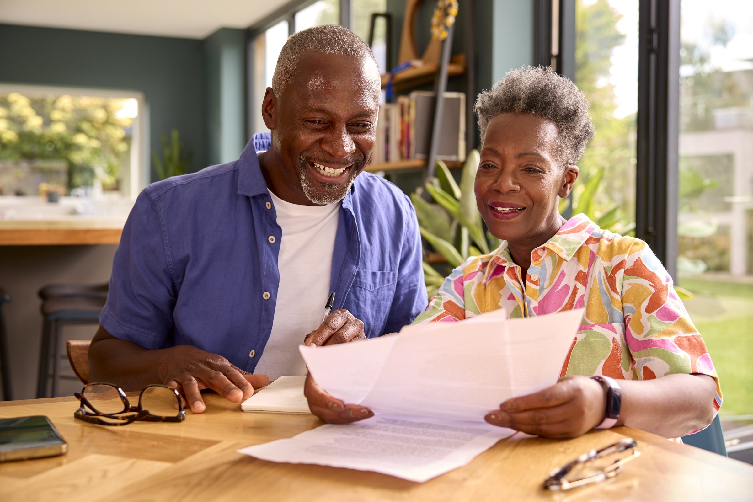 A retired couple at their kitchen table, smiling over their statements