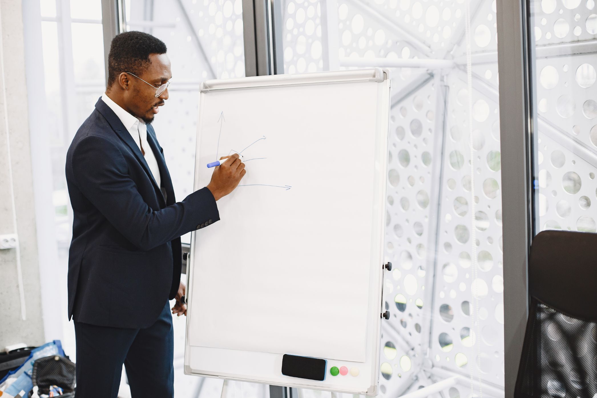 A man in a suit writing on a flip chart at the front of a room