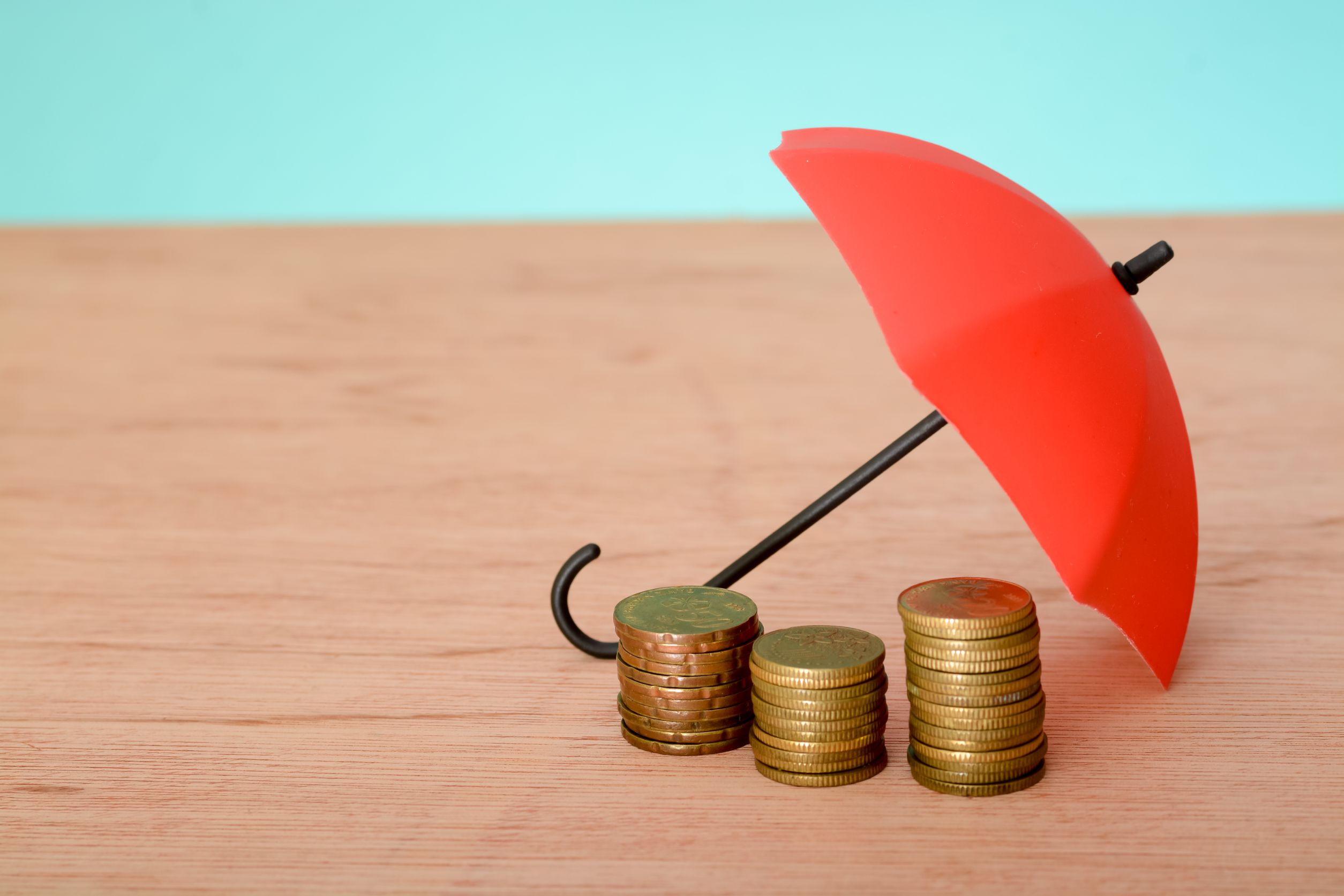 A small red umbrella sheltering three stacks of coins